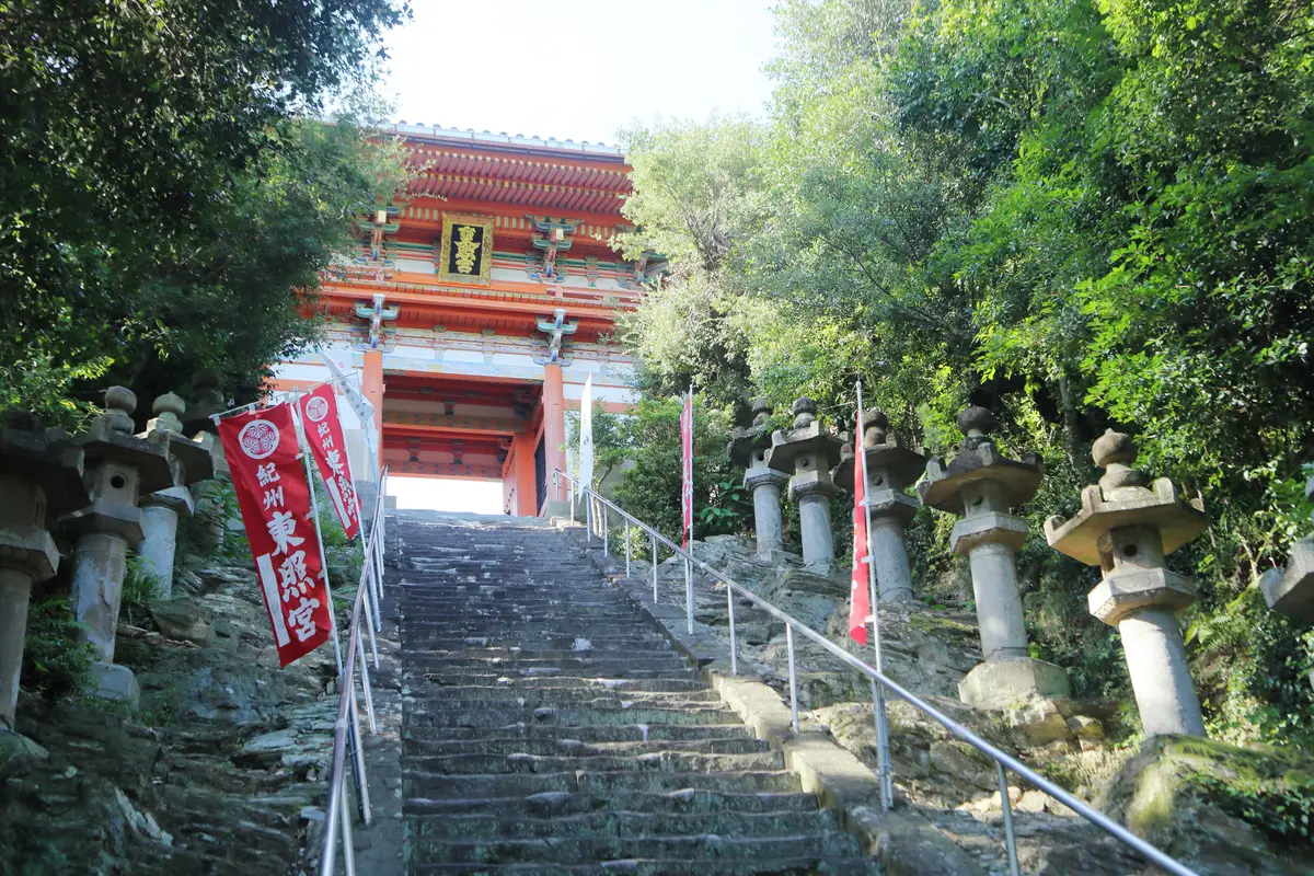 兩側排列石燈籠的陡峭石階，通往紀州東照宮的朱紅色大門